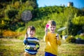 Active preschool girl and boy playing badminton in outdoor court in summer. Kids play tennis. School sports for children. Racquet