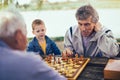 Senior men having fun and playing chess at park Royalty Free Stock Photo