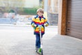 Active school kid boy in colorful casual clothes riding with his scooter in the city Royalty Free Stock Photo