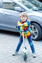 Active school kid boy in colorful casual clothes riding with his scooter in the city Royalty Free Stock Photo