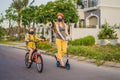 Active school kid boy and his mom in medical mask and safety helmet riding a bike with backpack on sunny day. Happy Royalty Free Stock Photo