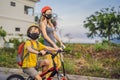 Active school kid boy and his mom in medical mask and safety helmet riding a bike with backpack on sunny day. Happy Royalty Free Stock Photo