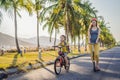 Active school kid boy and his mom in safety helmet riding a bike with backpack on sunny day. Happy child biking on way