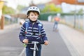 Active school kid boy in safety helmet riding with his scooter in the city with backpack on sunny day. Happy child in Royalty Free Stock Photo