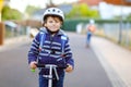 Active school kid boy in safety helmet riding with his scooter in the city with backpack on sunny day. Happy child in