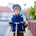 Active school kid boy in safety helmet riding with his scooter in the city. Happy child in colorful clothes biking on Royalty Free Stock Photo