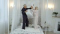 Active happy senior Caucasian grandparents couple jumping, having pillow fight on bed at home Royalty Free Stock Photo