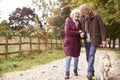 Active Senior Couple On Autumn Walk With Dog On Path Through Countryside Royalty Free Stock Photo