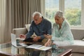 Active senior couple calculating bills in living room Royalty Free Stock Photo