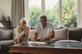 Active senior couple calculating domestic bills on sofa in living room Royalty Free Stock Photo