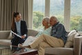 Active senior couple discussing with real estate agent over documents in living room Royalty Free Stock Photo