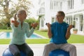 Active senior couple exercising with dumbbell in porch at home Royalty Free Stock Photo