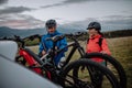 Active senior couple loading their bicycles on car carrier outdoors in nature in autumn day. Royalty Free Stock Photo