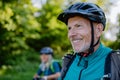 Active senior couple riding bicycles at summer park, man with bicycle helmet, healthy lifestyle concept. Royalty Free Stock Photo