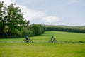Active senior couple riding electric bicycles on trail at summer park, healthy lifestyle concept. Side view. Royalty Free Stock Photo