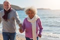 Active Senior Couple Running Along Winter Beach By Waves Holding Hands Royalty Free Stock Photo