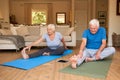 Active senior couple stretching while doing yoga together at home