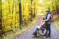 Senior couple with wheelchair in autumn forest.