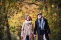 Senior couple walking in a forest in an autumn nature, holding hands.