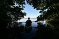 Active senior kayaker silhouetted against blue sky under mangrove canopy.