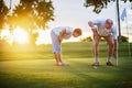 Active senior lifestyle, elderly couple playing golf together at sunset Royalty Free Stock Photo