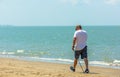 Active senior man walking with nordic walking poles on the beach
