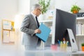 Active senior office worker taking blue fold from the shelves