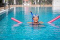 Active senior woman doing exercise in swimming pool with swim noodles. Happy retired people in the outdoor pool water under the Royalty Free Stock Photo