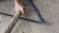 Active senior woman hands using bow saw cutting bamboo stick for craftwork woodworking at home ground