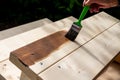 Active senior woman painting some pieces of wood, timber by brown paint colour with brush.worker painting a wooden wall Royalty Free Stock Photo