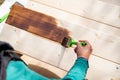 Active senior woman painting some pieces of wood, timber by brown paint colour with brush.worker painting a wooden wall Royalty Free Stock Photo