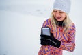 Active senior woman runner adjusting smartphone, attached to arm, for exercising outdoors in snowy winte.