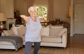 Active senior woman smiling and doing yoga alone at home
