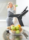 Active senior woman in sportswear drinking water while walking on a treadmill at home Royalty Free Stock Photo