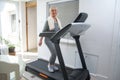 Active senior woman in sportswear using treadmill at home. Coronavirus Covid19 social distance. Royalty Free Stock Photo