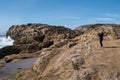 Active senior woman stands on the slippery rocks of Point Lobos State Reserve in California, admiring the scenery and taking