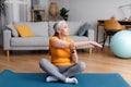 Active senior woman stretching her arm on mat at home, doing flexibility exercises, practicing yoga or pilates Royalty Free Stock Photo