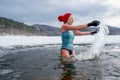 Active senior woman in swimsuit outdoors in winter in frozen lake, cold therapy concept.