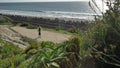 Active Senior woman walking at pedestrian trail close to ocean with beautiful landscapes at summer day in california san