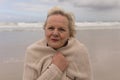 Active senior woman wrapped in jumper on the beach Royalty Free Stock Photo