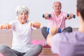 Active seniors during exercises on gym with young instructor
