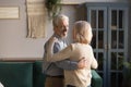 Grey-haired husband embraces blond wife couple dancing at home