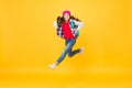 Active small kid run with travel bag listening to music in headphones yellow background, traveling