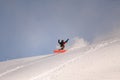 active snowboarder in bright overalls slides down the mountain on splitboard on powdery snow