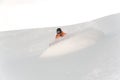 Active snowboarders in orange sportswear riding down the mountain slope against the white sky