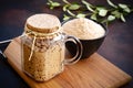 Active sourdough starter in glass jar. Rye leaven for bread and cup of flour on wooden cutting board on dark background. Close-up Royalty Free Stock Photo