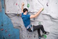 Active sporty man wearing protective face mask practicing rock climbing on artificial rock in a climbing wall Royalty Free Stock Photo