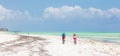 Active sporty tourist couple cycling down picture perfect white sand tropical beach of Paje, Zanzibar, Tanzania.