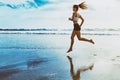 Active sporty woman run along sunset ocean beach. Sports background.