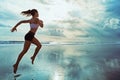 Active sporty woman run along sunset ocean beach. Sports background. Royalty Free Stock Photo